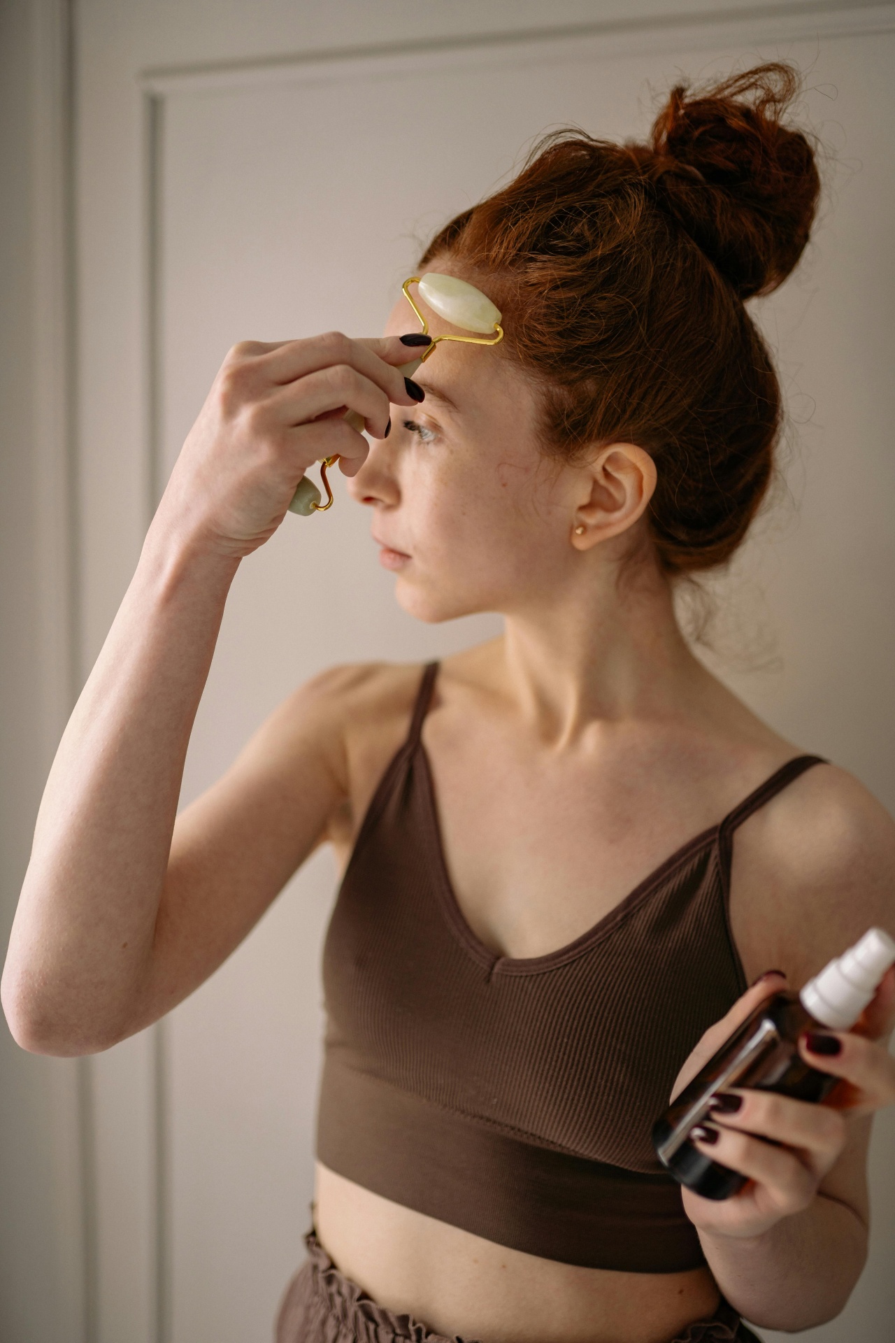Woman using jade roller on her cheek