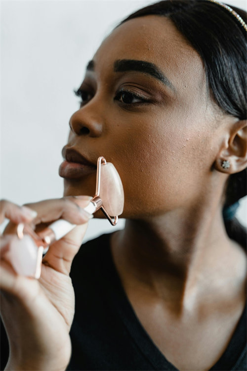 Woman using jade roller with gentle pressure for mature perimenopausal skin care