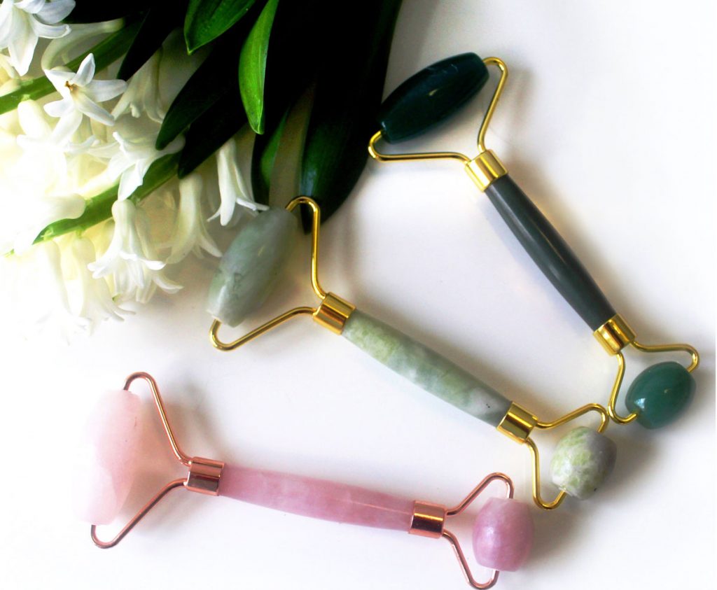 A bride at a vanity with a jade roller and a glass of water