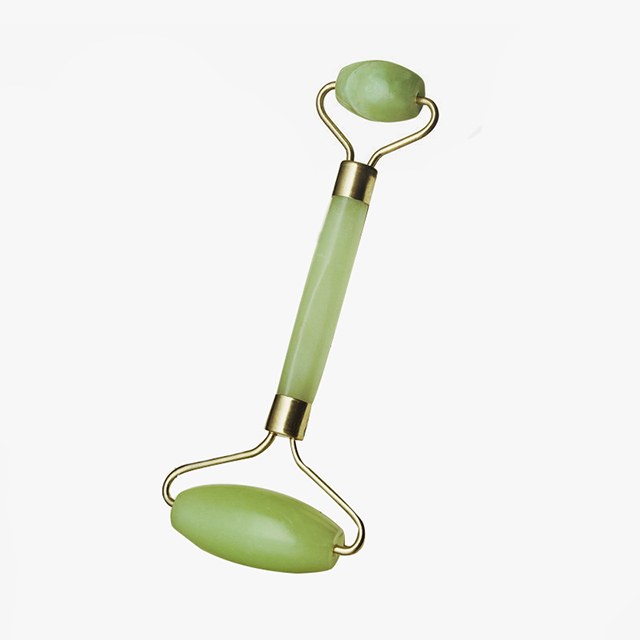 A woman rolling her arm with a jade roller from hand toward shoulder