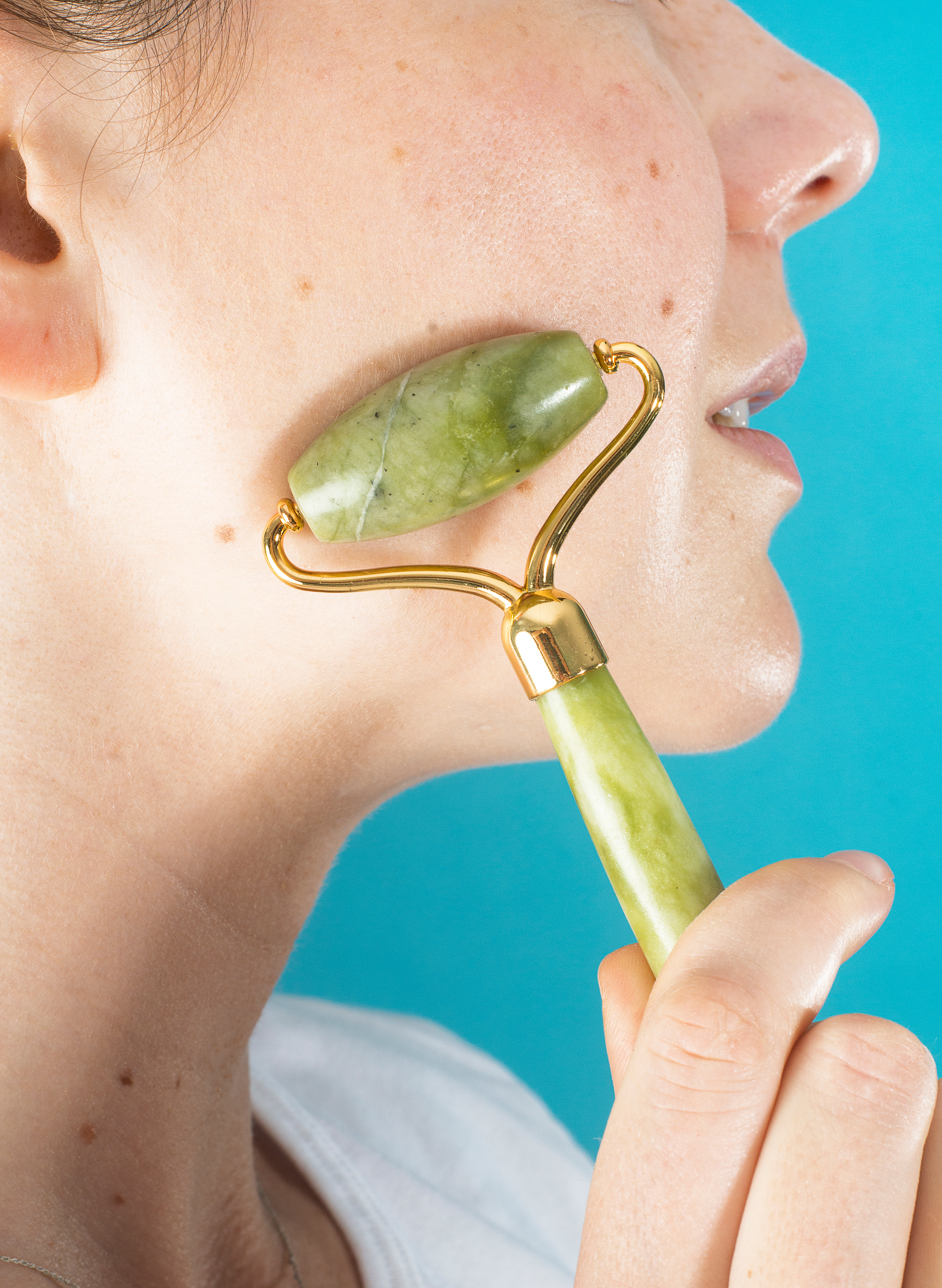 jade roller gliding on cheek with light pressure
